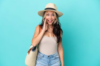 Pamel ve plaj çantalı genç Rus kız mavi arka planda, şaşırmış ve şok olmuş bir yüz ifadesi var.