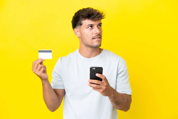 Mladý Kavkazský Pohledný Muž Izolované Žlutém Pozadí Nákup Mobilem Kreditní — Stock fotografie