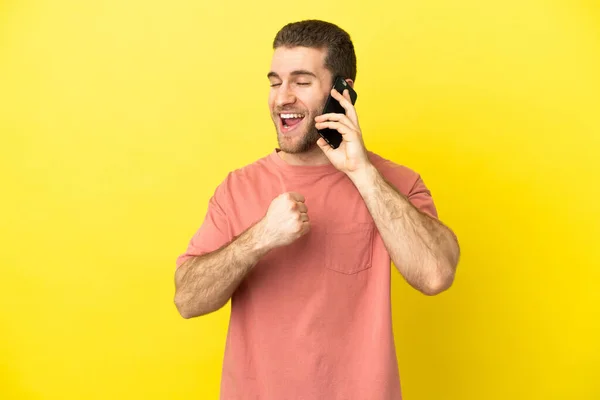Hezké Blondýny Muž Pomocí Mobilního Telefonu Přes Izolované Pozadí Slaví — Stock fotografie