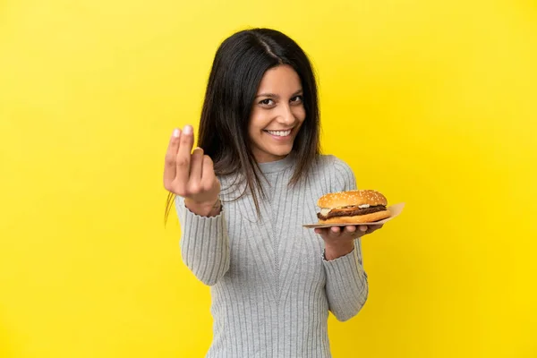 Młoda Kaukaska Kobieta Trzyma Hamburgera Odizolowanego Żółtym Tle Robiąc Gesty — Zdjęcie stockowe