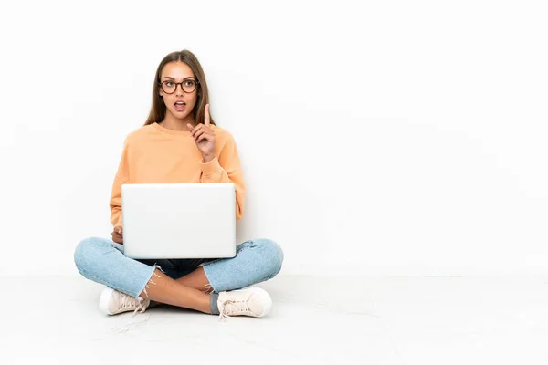 一个拿着笔记本电脑坐在地板上的年轻女人在想办法指指点点 — 图库照片