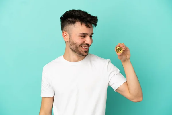 Mladý Muž Drží Bitcoin Izolované Modrém Pozadí Dívá Strany Usmívá — Stock fotografie