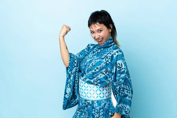 Νεαρή Γυναίκα Που Φοράει Κιμονό Πάνω Απομονωμένο Μπλε Φόντο Γιορτάζει — Φωτογραφία Αρχείου