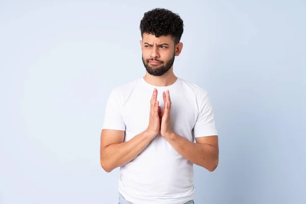 Young Moroccan man isolated on blue background scheming something