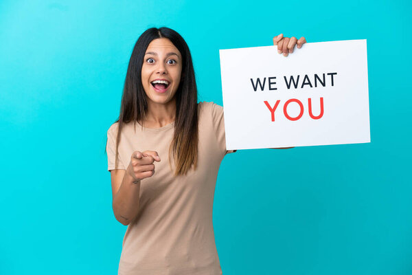 Young woman over isolated background holding We Want You board and pointing to the front