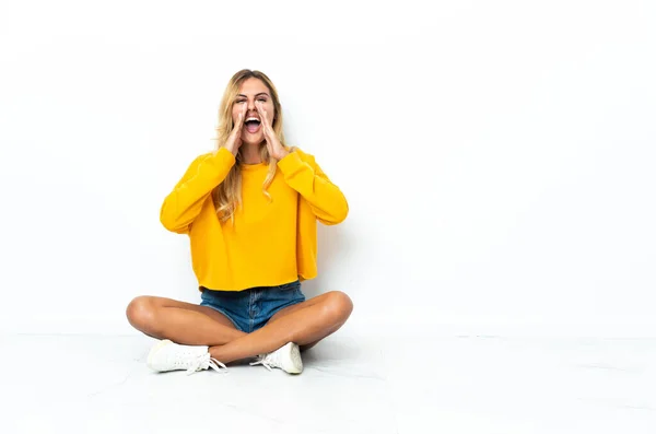 Jonge Blonde Uruguayaanse Vrouw Zit Vloer Geïsoleerd Witte Achtergrond Schreeuwen — Stockfoto