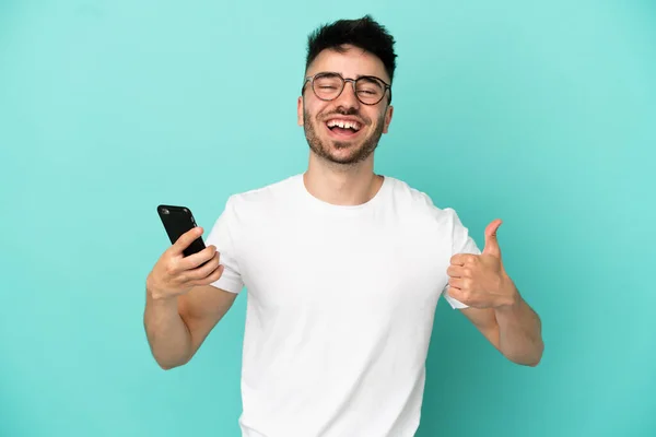 Mladý Kavkazský Muž Izolované Modrém Pozadí Pomocí Mobilního Telefonu Zatímco — Stock fotografie