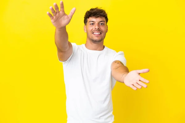 Junger Kaukasischer Gutaussehender Mann Auf Gelbem Hintergrund Präsentiert Und Lädt — Stockfoto