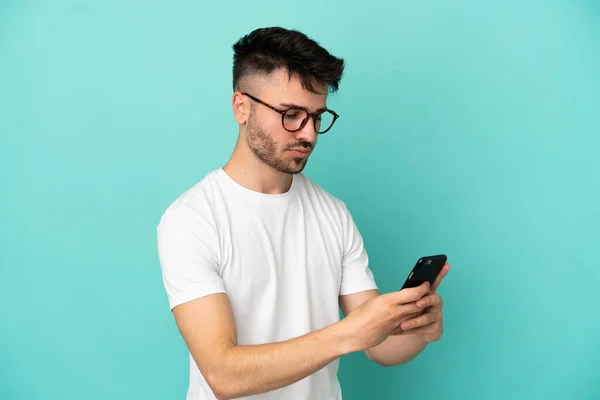 Mavi Arka Planda Izole Edilmiş Genç Beyaz Adam Cep Telefonuyla — Stok fotoğraf