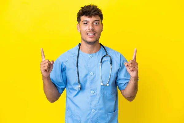 Młody Chirurg Lekarz Człowiek Izolowany Żółtym Tle Wskazując Świetny Pomysł — Zdjęcie stockowe