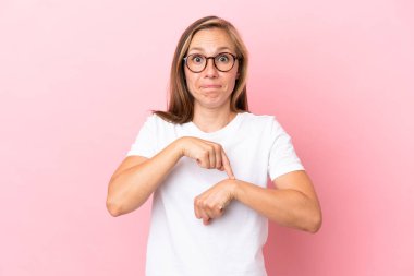 Pembe arka planda izole edilmiş genç İngiliz kadın geç kalma jesti yapıyor.