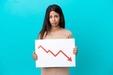 İzole edilmiş arka planda, elinde acı ifadeli, azalan bir istatistik ok sembolü olan bir tabela tutan genç bir kadın.