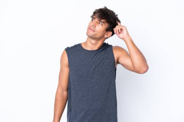 Beyaz arka planda soyutlanmış beyaz tenli genç bir adamın şüpheleri ve kafası karışmış bir yüz ifadesi var.