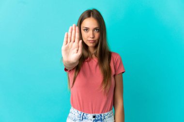 Soyutlanmış mavi arka plan hareketlerini durduran genç bir kadın.