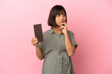 Aşırı izole edilmiş hamile bir kadın ve elinde çikolata tutarken şüpheleri var.