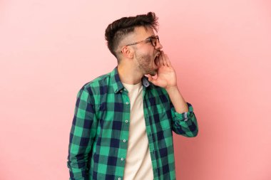 Pembe arka planda izole edilmiş genç beyaz adam ağzı sonuna kadar açık bağırıyor.
