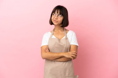 Pembe arka planda bir restoran garsonu gülümserken yukarı bakıyor.