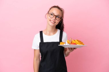Restoran garsonu. Elinde waffle tutan Rus kız. Pembe arka planda izole edilmiş.