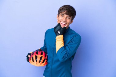 Mor arka planda izole edilmiş genç beyaz adam mutlu ve gülümsüyor.