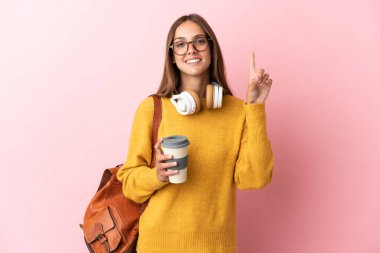 Tecrit edilmiş pembe arka planı olan genç bir bayan en iyinin işareti olarak parmağını kaldırıyor.