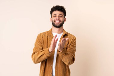 Bej arka planda izole edilmiş genç Faslı bir adam bir konferansta sunumdan sonra alkışlıyor.