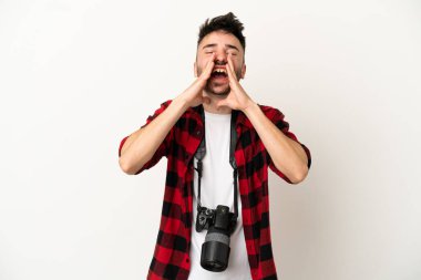 Beyaz arka planda izole edilmiş genç fotoğrafçı bağırıyor ve bir şey duyuruyor.