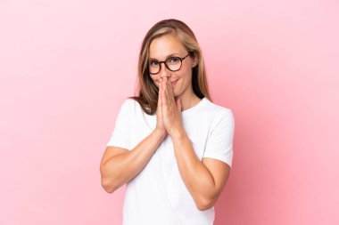 Pembe arka planda izole edilmiş genç İngiliz kadın avuç içlerini bir arada tutuyor. İnsan bir şey ister.