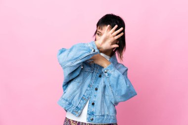 Genç Uruguaylı kadın soyutlanmış pembe arka planda gergin eller öne doğru uzanıyor.