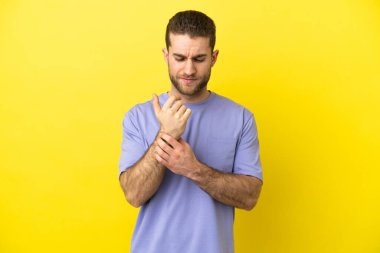 Sarışın yakışıklı adam izole edilmiş sarı arka planda acı çekiyor.