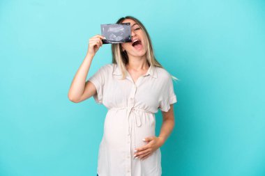 Genç Romen kadın mavi arka planda izole edilmiş hamile ve ultrason çekiyor