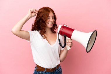 Pembe arka planda izole edilmiş genç bir kadın megafonla bir şey duyurmak için bağırıyor.