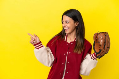Beyzbol oynayan beyaz bir kadın sarı arka planda izole edilmiş bir şekilde parmak ucunda bir ürün sunuyor.
