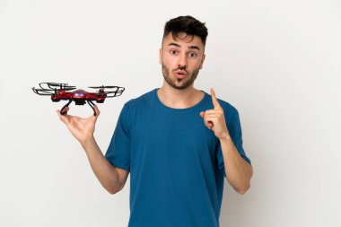 Beyaz arka planda izole edilmiş insansız hava aracı tutan adam parmağını kaldırırken çözümü fark etmeyi amaçlıyor.