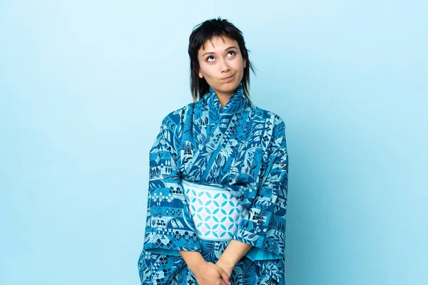 Mujer Joven Usando Kimono Sobre Fondo Azul Aislado Mirando Hacia —  Fotos de Stock
