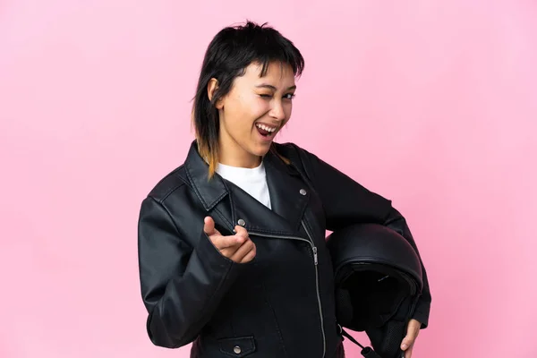 年轻的乌拉圭女人拿着摩托车头盔在孤立的粉色背景下指着你 — 图库照片