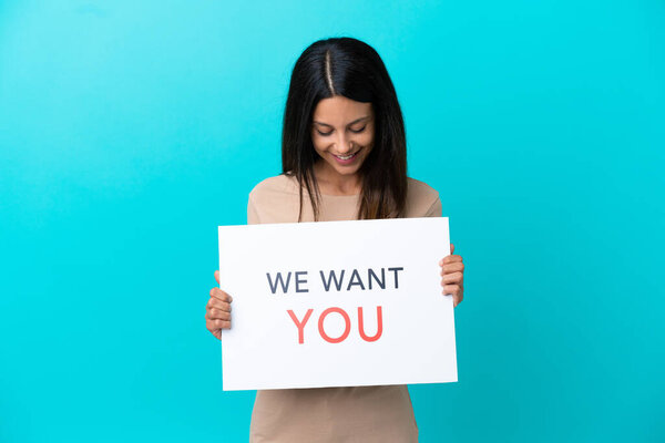 Young woman over isolated background holding We Want You board
