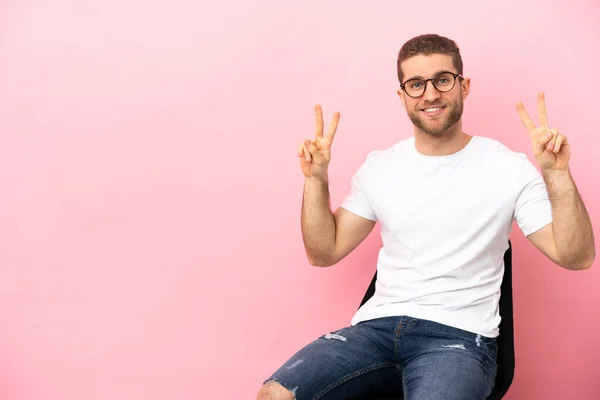 Mladý Muž Sedí Židli Nad Izolovaným Růžovým Pozadím Oběma Rukama — Stock fotografie