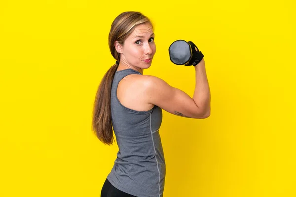 若い英語の女性は黄色の背景に隔離された重量挙げを作る — ストック写真