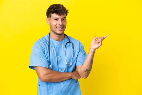 Молодий Хірург Лікар Чоловік Ізольований Жовтому Тлі Вказуючи Пальцем Бік — стокове фото