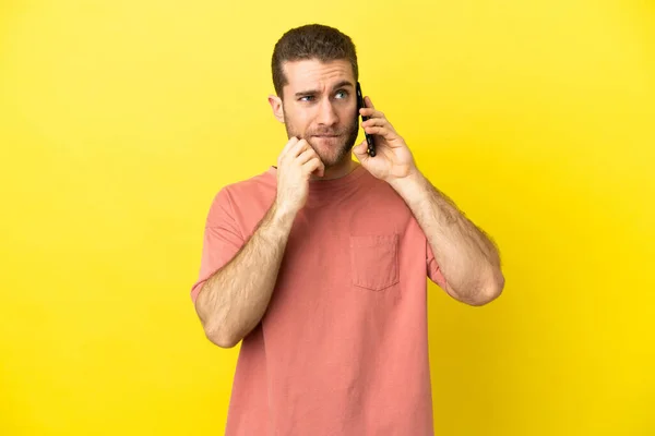 Hezké Blondýny Muž Pomocí Mobilního Telefonu Přes Izolované Pozadí Pochybnostmi — Stock fotografie