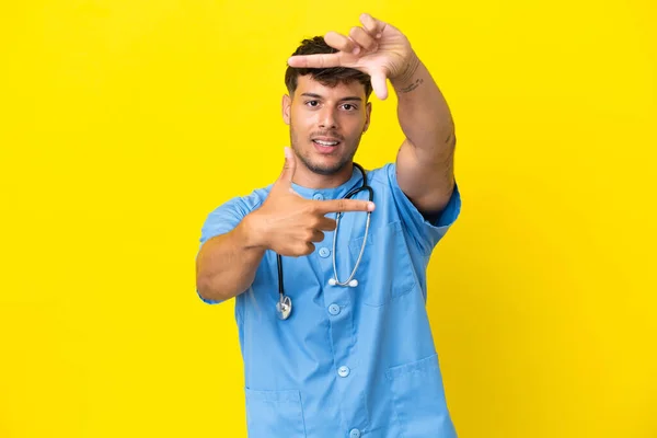 若い外科医の医師の男性は黄色の背景に焦点を当て顔に隔離された フレーミングシンボル — ストック写真