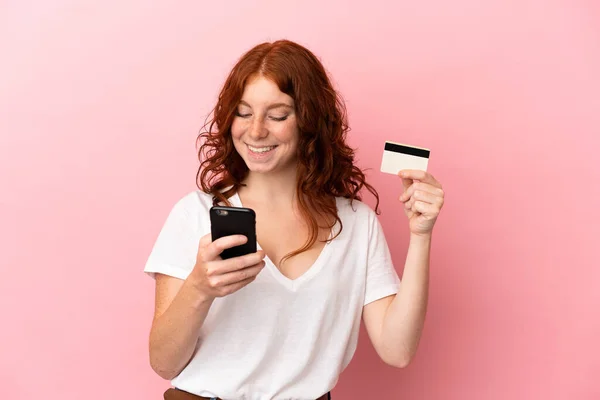 Tiener Roodachtige Vrouw Geïsoleerd Roze Achtergrond Kopen Met Mobiele Telefoon — Stockfoto