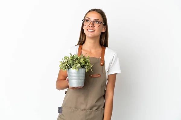 Gärtnermädchen Hält Eine Pflanze Über Isoliertem Weißen Hintergrund Und Denkt — Stockfoto
