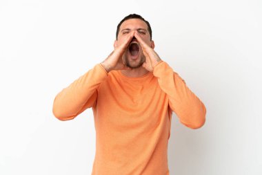 İzole edilmiş beyaz arka planda Brezilyalı bir adam bağırıyor ve bir şey duyuruyor