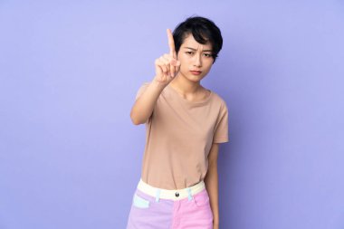 Mor arka planda, kısa saçlı, genç Vietnamlı bir kadın ciddi bir ifadeyle sayıyor.