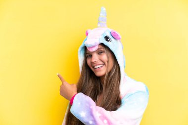 Sarı arka planda izole edilmiş tek boynuzlu at pijaması giyen beyaz bir kadın.