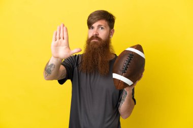 Kızıl saçlı beyaz adam sarı arka planda ragbi oynuyor.