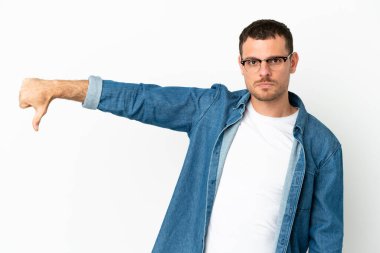 İzole edilmiş beyaz arkaplan üzerinde Brezilyalı bir adam negatif ifadeyle baş parmağını aşağı gösteriyor