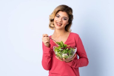 Mavi arka planda salatalı genç bir kadın.