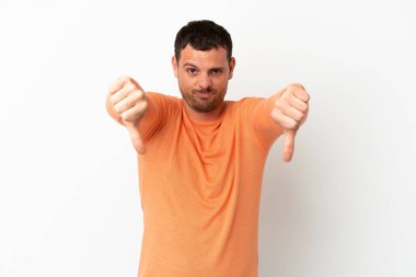 İzole edilmiş beyaz arka plan üzerinde Brezilyalı bir adam baş parmağını iki eliyle aşağı gösteriyor.